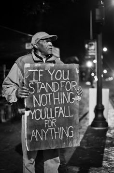 a man holding a sign that says if you stand for nothing, no fail for anything