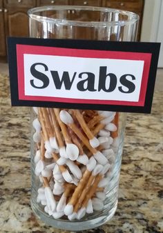 a glass filled with marshmallows sitting on top of a counter next to a sign that says swabs