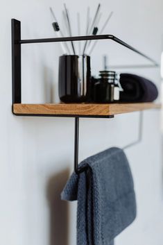 a wooden shelf with some black items on it and a towel hanging from the wall