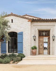 a house with blue shutters and an olive tree