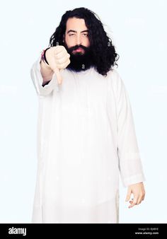 a man with long hair and beard giving the thumbs up sign, wearing white clothing - stock image