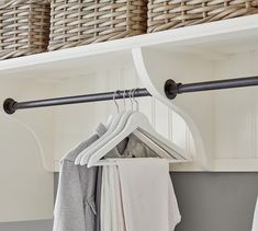 an organized closet with hanging clothes and baskets