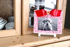 a dog with a red bow on it's head sitting in front of a window