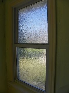 a window with frosted glass on the outside and inside, in front of a green wall