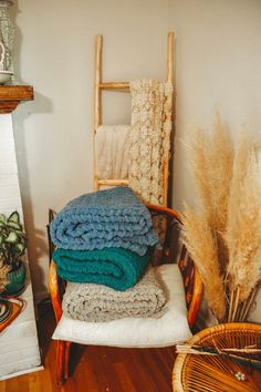 a stack of blankets sitting on top of a wooden chair next to a fire place