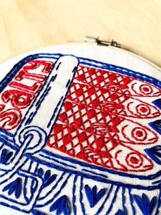 a red white and blue embroidered object sitting on top of a wooden table