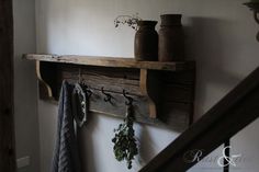 an old wooden shelf with two vases on it and hooks hanging from the wall