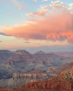 the clouds are pink and orange as the sun sets in the distance at the grand canyon