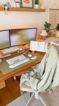 a computer desk with two monitors and a keyboard on it, covered in a blanket