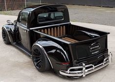 an old black pickup truck parked in a parking lot