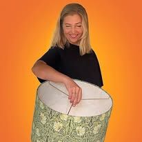 a woman is smiling while holding a large object in front of an orange background and she has her eyes closed