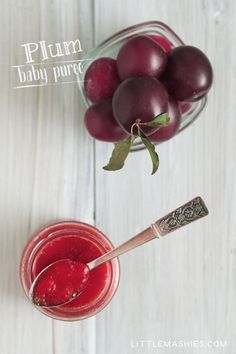 plum baby puree in a glass jar next to a bowl of plums