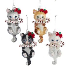 three ornaments in the shape of cats holding candy canes