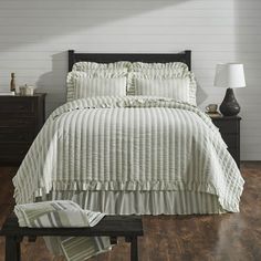 a white bed sitting on top of a wooden floor next to a nightstand and lamp