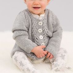 a baby sitting on top of a white rug wearing a sweater and leggings