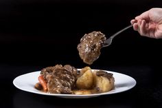 a person is spooning some food out of a white plate