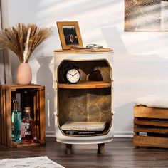 a small white cabinet with a clock on top and other items in front of it