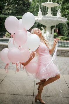 a woman in a pink dress holding balloons