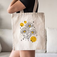 a woman carrying a tote bag with daisies on it