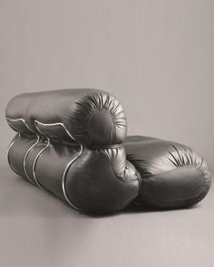 two black and white pillows sitting on top of each other in front of a gray wall