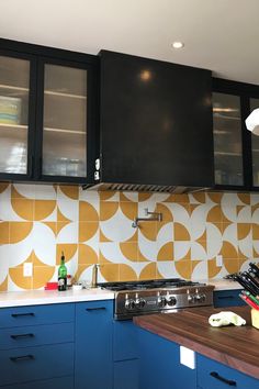 a kitchen with blue cabinets and yellow patterned backsplash