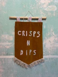 a sign that says crisps n dips hanging from a clothes line on a wall