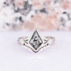 a white diamond ring sitting on top of a marble slab with diamonds around it's edges