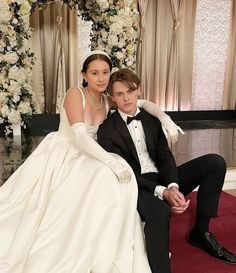 a bride and groom pose for a photo in front of a floral arch at their wedding