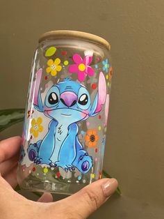 a hand holding up a glass with an image of stitcher from the disney movie stitchers