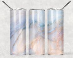 three stainless steel tumblers with marble designs on them, one is empty and the other has a straw in it