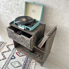 an old record player is sitting on top of a wooden stand with drawers and records