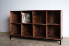 a wooden shelf with books and magazines in it on the floor next to a wall