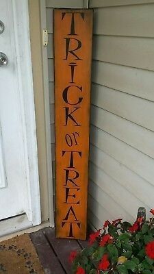 a wooden sign that says trick or treat on the side of a house next to flowers