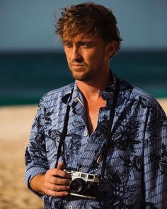 a man standing on the beach holding a camera