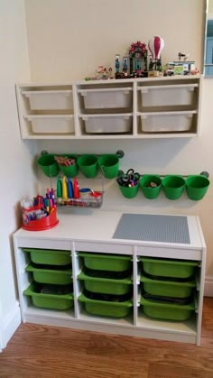 a playroom with green bins and white shelves