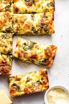 several slices of pizza sitting on top of a white counter next to cheese and sauce