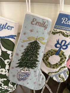 three christmas stockings hanging from hooks on the wall, decorated with holiday ornaments and words