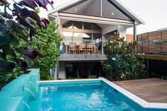 an outdoor swimming pool surrounded by greenery next to a deck and fenced in area