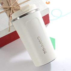 a white coffee cup sitting next to a wrapped present