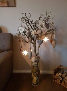 a tree with ornaments hanging from it's branches in a vase next to a couch