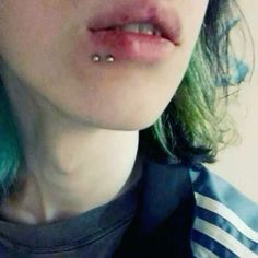 a close up of a person with green hair and piercings on their nose, wearing a striped shirt