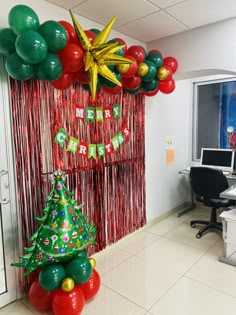 an office decorated for christmas with red, green and gold balloons hanging from the ceiling