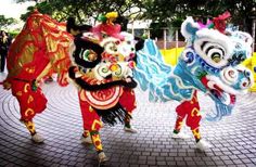 three colorful lion dance costumes on display in front of people wearing red and yellow outfits