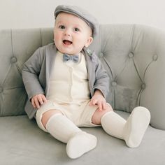 Handmade in the USA Elegantly crafted from our premium French Terry cotton, the luxurious Ezra Baby Boy Suit offers a delightful, unique feel. The jacket features a fold-over collar, pockets, and buttons, creating a sophisticated look perfect for any special event. The set includes a tan vest, pants or shorts, ivory onesie, and heather jacket, ideal for transitioning from ceremony to celebration. Finish off the ensemble with the matching newsboy cap and Ezra booties or a pair of our suede shoes. White Bubble Romper For Baptism, White Short Sleeve Onesie For Baptism, White Summer Onesie For Baptism, Cotton Baptism Onesie With Short Sleeves, Personalized Fitted Onesie For Baptism, Tan Vest, Baby Boy Suit, Heirloom Gifts, Long Sleeve Onesie