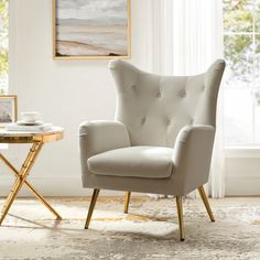 a white chair sitting in front of a window next to a table with a cup on it