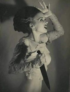 an old photo of a woman holding a knife up to her face with both hands