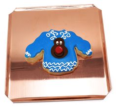 a cookie shaped like a blue sweater with a red nose