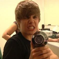 a young man holding a hair dryer in his hand