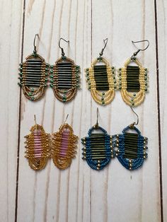 four pairs of beaded earrings sitting on top of a wooden table