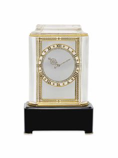 a white and gold clock sitting on top of a black stand in front of a white background